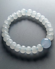 Beaded bracelet with a single blue gemstone on a gray background